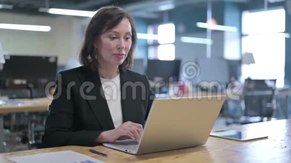 成功的中年女商人用手提电脑庆祝视频的预览图
