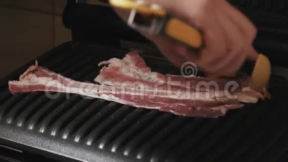 厨师把一片新鲜培根放在电子家庭烤架上视频的预览图