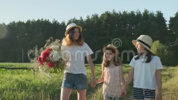 孩子们是三个女孩手捧鲜花走在乡间小路上视频的预览图