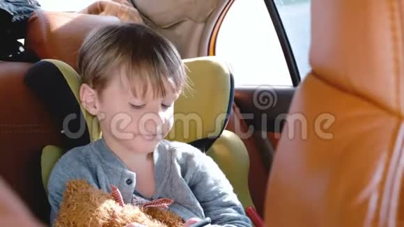 快乐的小46岁欧洲男孩使用智能手机娱乐应用程序在汽车儿童安全座椅在白天乘坐视频的预览图