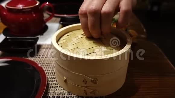 一个男人手在柳条木盒里展示传统的日本食品点心里面有蔬菜蘑菇和竹酱视频的预览图