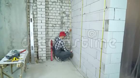 穿戴红帽的工人在混凝土砌块墙上安装金属栏杆视频的预览图