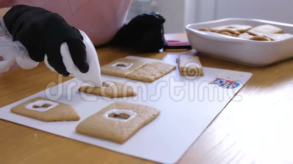 女人的手上装饰着糖甜的姜饼屋用的冰曲奇烹饪自制姜饼屋视频的预览图