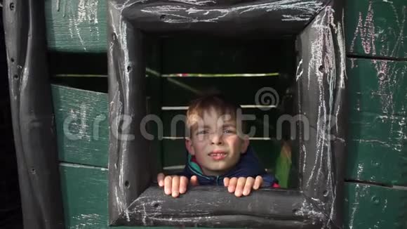 男孩从一扇木窗外望去做着鬼脸视频的预览图