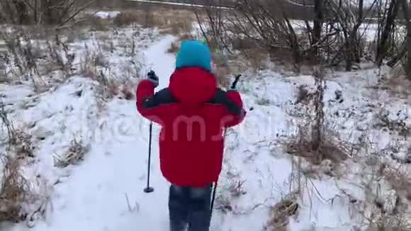 一个穿红色夹克的小男孩拿着拐杖在北欧散步视频的预览图