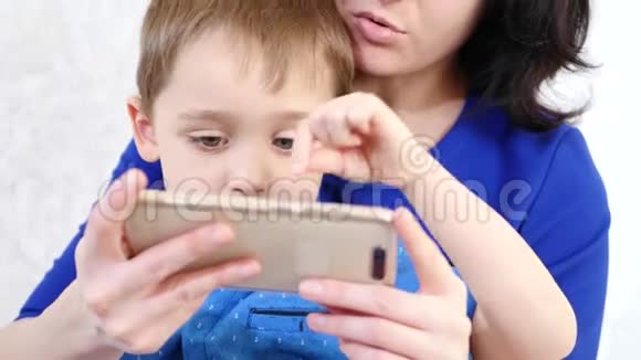 一个女人抱着一个小男孩拥抱他孩子触摸手机的触摸屏在一个游戏中玩孩子的游戏视频的预览图