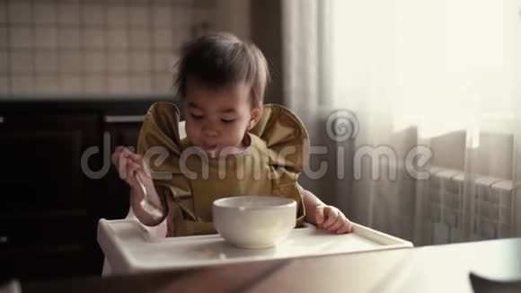 小可爱的女孩坐在孩子们椅子后面玩食物视频的预览图