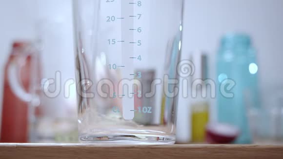 慢动作将水倒入厨房桌子上的玻璃量杯视频的预览图