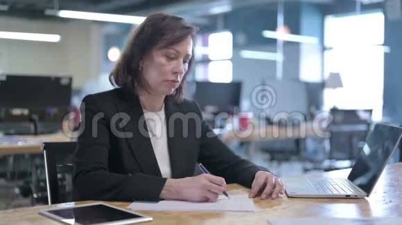 勤劳的中年女商人试图在办公室里写论文视频的预览图