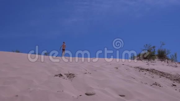 暑假小男孩从海边的巨大沙丘上跑跳跳视频的预览图