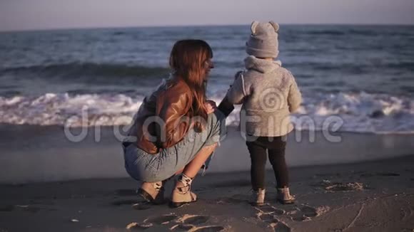 一个母亲和她的孩子在大海或海洋上的背面镜头可爱的小宝宝站在水上看着视频的预览图