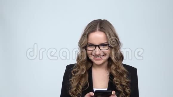 一个微笑的女人在录音室里用灰色背景发短信动作很慢视频的预览图