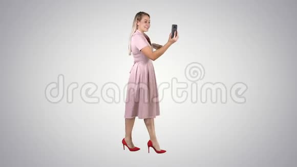粉红女郎手持智能手机录制视频博客在渐变背景下行走视频的预览图