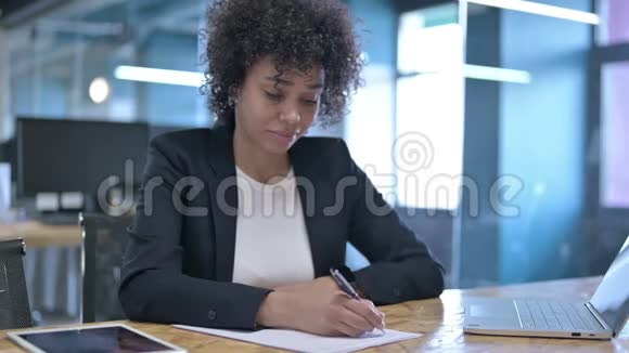 愉快的非洲女商人在办公室工作时写论文视频的预览图