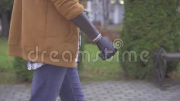 一个戴着网络假肢的年轻人正在公园里近距离行走视频的预览图
