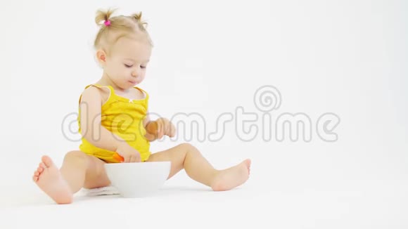 金发小女婴在白色背景下吃早餐视频的预览图