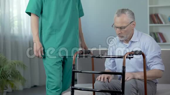 悲伤的人站在康复中心用步行架移动视频的预览图