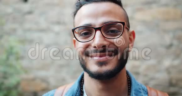 戴眼镜的阿拉伯帅哥站在户外的特写照片视频的预览图