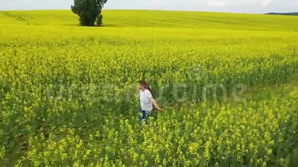 日落时分女孩在一片黄色的花坛上奔跑无人机镜头户外娱乐视频的预览图