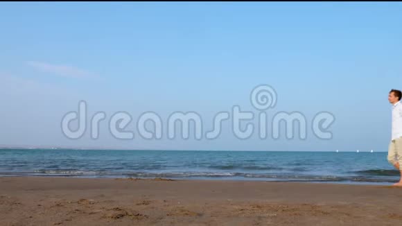 日落时分幸福浪漫的情侣漫步在海滩上视频的预览图