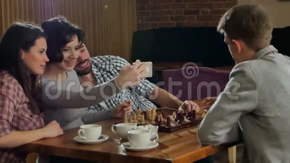 年轻夫妇和朋友在室内下棋并自拍视频的预览图