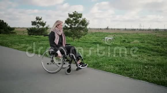 阳光明媚的一天快乐的年轻女子在公园里坐轮椅旋转着身体视频的预览图