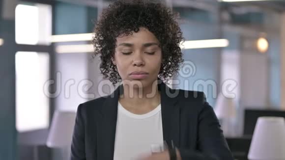 焦虑的非洲女商人在检查她的智能手表时等待某人的画像视频的预览图