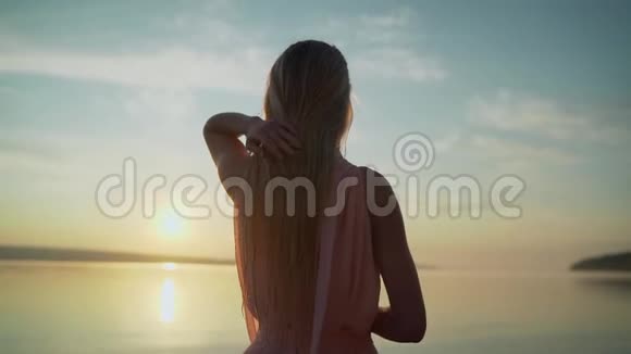 日出时穿着浅色裙子的女孩黎明时分穿着浅粉色连衣裙在海滩上散步的美丽女子视频的预览图