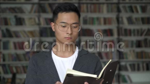 在书架的背景下读着一本便条思考的年轻人视频的预览图
