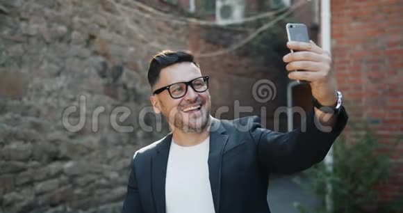 快乐的中年男子带着智能手机相机在户外微笑自拍视频的预览图