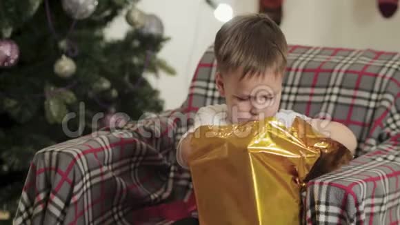 孩子坐在圣诞树下打开礼物视频的预览图