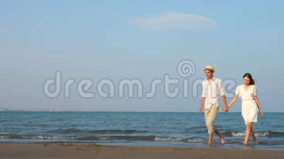 恋爱中的年轻夫妇在沙滩慢动作的优雅服装中享受浪漫视频的预览图