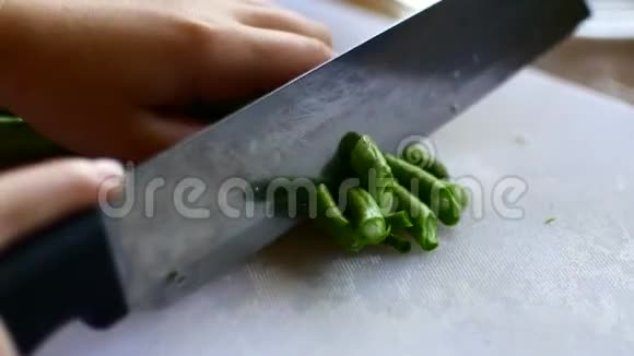 孩子帮着做饭用刀切一串豆子然后把它转到锅里视频的预览图