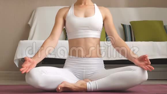 年轻女子正在家里练习瑜伽以简单的身体姿势坐在地板上放松视频的预览图