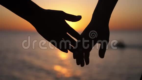 一对相爱的年轻夫妇手牵着手在日落时分奔向大海玩得很开心慢动作视频的预览图