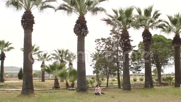 一个小男孩跑到棕榈树之间拥抱了他的母亲慢动作视频的预览图