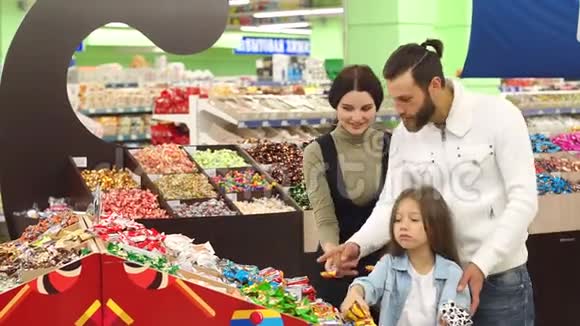 快乐的父母带着一个小女儿在糖果店买巧克力视频的预览图