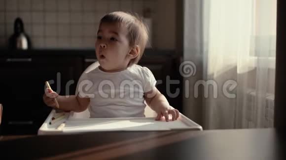小可爱的女婴坐在儿童椅的桌子旁打哈欠视频的预览图