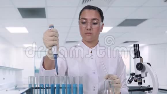 一位女科学家用微型吸管和试管检查蓝色液体一位女性研究员正在进行临床研究视频的预览图