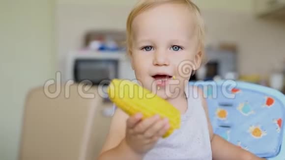 可爱可爱的白人金发男孩坐在厨房的高脚椅上享受着美味的甜煮玉米快乐视频的预览图