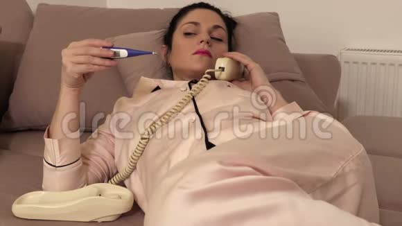 有复古手机和温度计的女人躺在沙发上视频的预览图