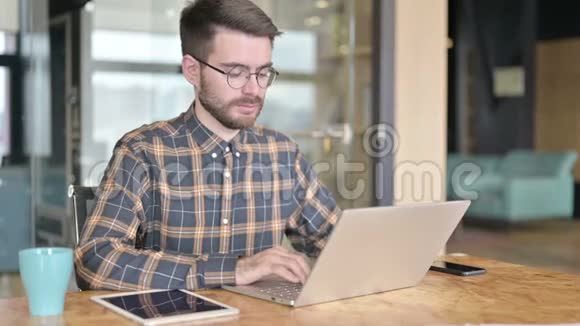 年轻设计师用笔记本电脑做现代办公室视频的预览图