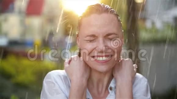快乐的年轻微笑的女人在雨天有乐趣开朗的女士有湿发在夏季公园视频的预览图