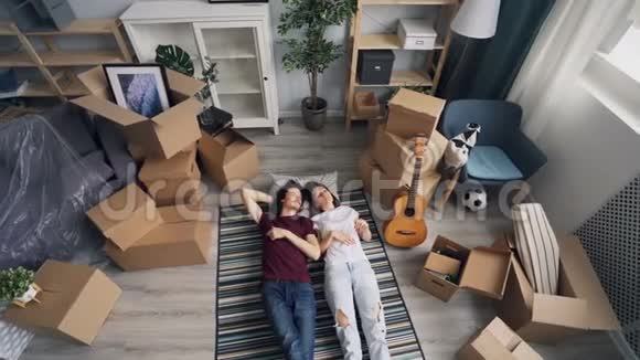 女孩和男人在搬到新公寓后躺在地板上聊天和打手势视频的预览图