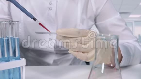 戴着手套的手的特写微型吸管血液测试和显微镜幻灯片视频的预览图