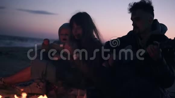可爱白种人一家三口坐在篝火旁父亲弹吉他年轻的长发女人喂食视频的预览图