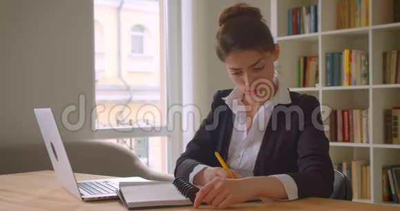 年轻漂亮的高加索女商人使用笔记本电脑并在办公室里用相机记录下来的特写镜头视频的预览图