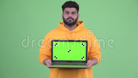 快乐的年轻超重留着胡子的印度男人一边说话一边拿着笔记本电脑视频的预览图