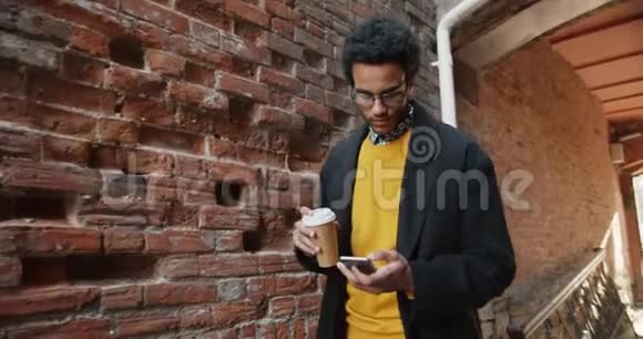 使用智能手机在户外喝咖啡的非裔美国学生慢动作视频的预览图