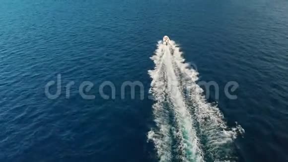 快速豪华游艇在海浪中飞驰在绿松石的海水上留下了泡沫痕迹在岩石前面视频的预览图